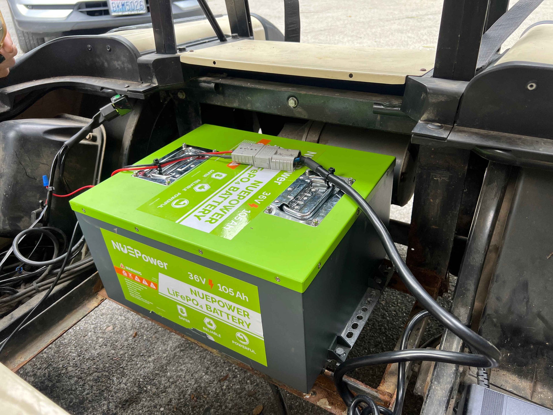 Close-up of a 36V 105Ah NUEPower battery installed in a golf cart with wiring visible.