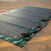 multiple solar panels laid flat on the ground with cables attached.