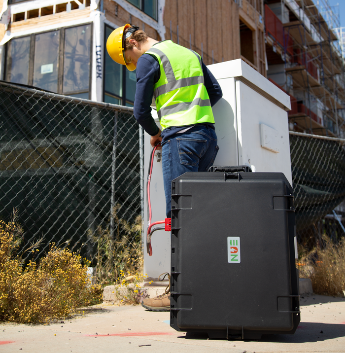 Broadband technician with a NUE battery generator at a network cabinet
