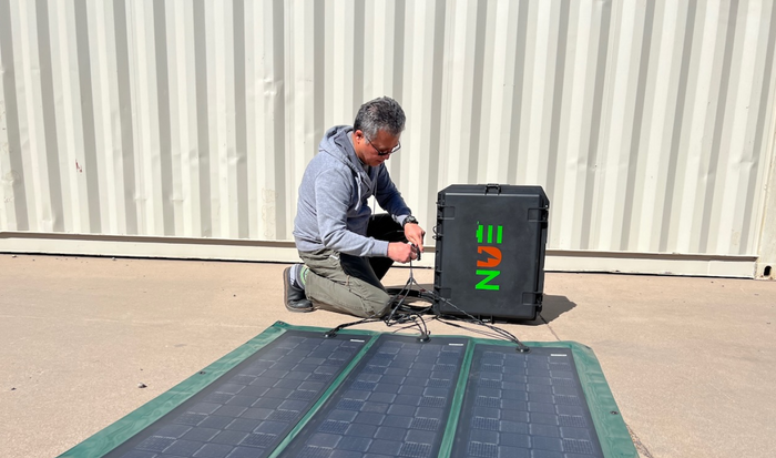 Worker deploying portable solar panels with a NUE battery generator